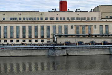 a factory on the river embankment with large striped pipes