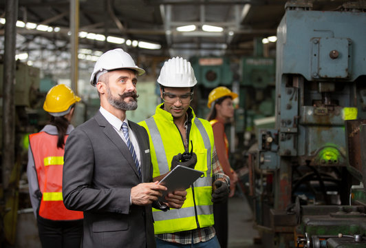Business director and Mechanic engineer checking and discussing at factory shop floor.