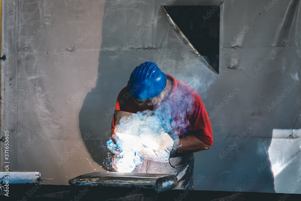 Wall mural a worker in the steel industry performs electric welding