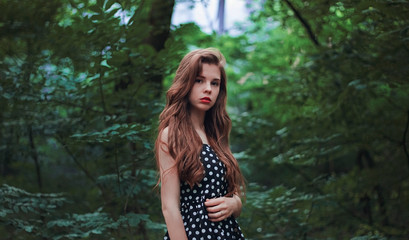 Naklejka premium Portrait of a bright girl with long hair in nature. Expressive eyes and red lips