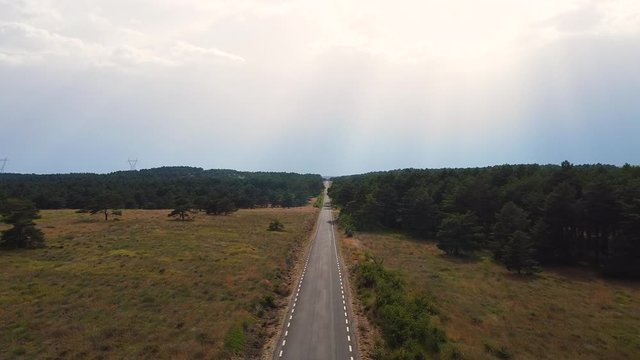 Furgoneta camper van por carretera recta con &aacute;rboles, dron al infinito