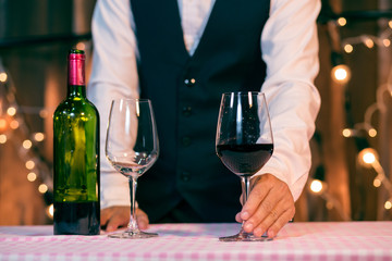 Waitress man pouring wine into glass