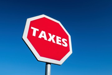 Stop TAXES sign in perspective view against blue sky to prevent state and government to take money from taxpayers