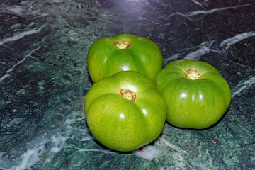 Green tomatoes over marble texture background.