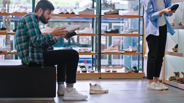 Good looking customer guy take a sit on the sofa in the shoe shop he make difference between shoes he wants to buy. Shot on ARRI Alexa Mini