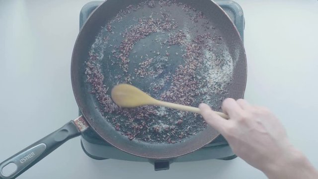 White Man's Hand Removes with a Wooden Spoon the Ingredients from the Black Frying Pan
