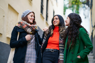 Multiethnic group of three happy woman walking together outdoors