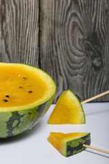 Pieces of yellow watermelon on sticks.