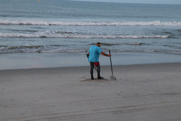 background, beach, beauty, calm, coast, colorful, Man Man with a metal detector walking along the beach searching for metal with waves splashing into the sands