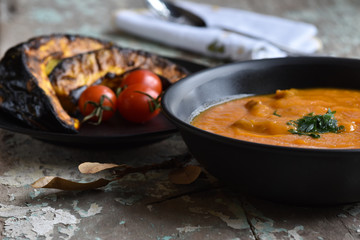 creme de abóbora e abóbora assadas com tomates sobre mesa rústica