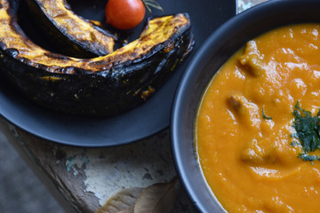 creme de abóbora e abóbora assadas com tomates sobre mesa rústica