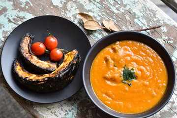 creme de abóbora e abóbora assadas com tomates sobre mesa rústica