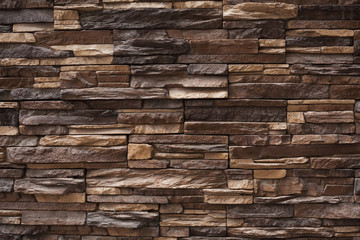 Background natural stone of different sizes and brown color. Wall cladding is textured