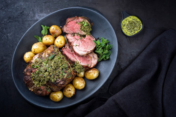 Traditional English barbecue lamb roast sliced with mint sauce and boiled potatoes sauce offered as...