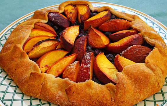 Homemade rustic galette pastry with fresh peaches and blueberries