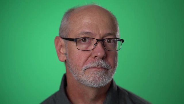 Slow motion closeup of man shocked, saying WOW. Handsome guy with bald gray hair surprised to camera on green screen background.