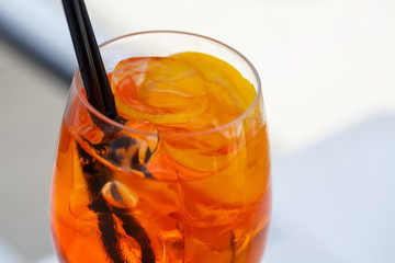 Refreshing light delicious summer aperol cocktail with ice and orange in a glass goblet, soft drink with straws for girls