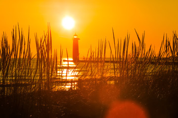 Lighthouse in Kenosha, Wisconsin at sunrise, focus on dune grasses - obrazy, fototapety, plakaty