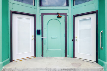 Choice of three doors on an old vintage teal colored building