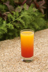 glass of orange juice with syrup in a glass on a green background