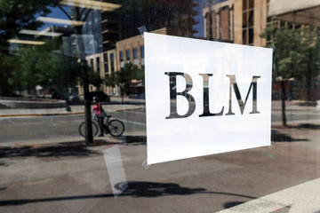 BLM standing for "Black Lives Matter" sign on a dirty downtown store window