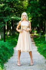 Obraz na płótnie Canvas Young beautiful blonde girl in beige dress, summer park outdoor