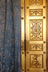 An old Golden door hidden behind a curtain. The fairy door. The concept of luxury and wealth.
