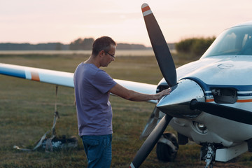 Pilot man standing next to a small private airplane