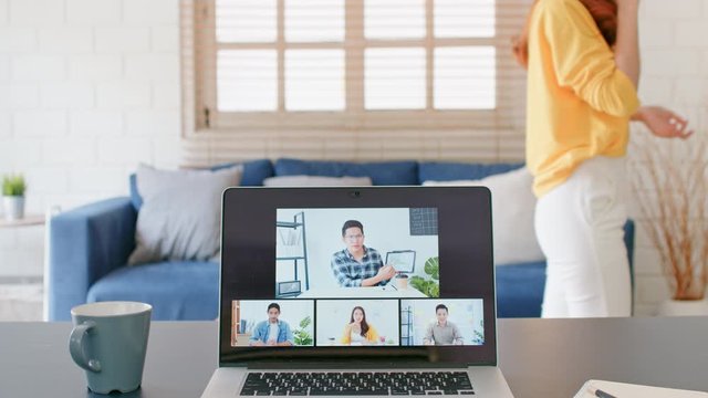 Young Asian woman on mobile phone call during video call conference, online remote meeting with business coworker at home. New normal lifestyle, social distancing, businesswoman work from home concept
