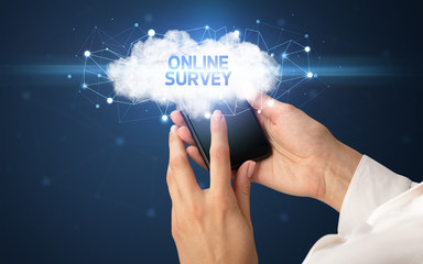 Female hand touching smartphone with ONLINE SURVEY inscription, cloud business concept