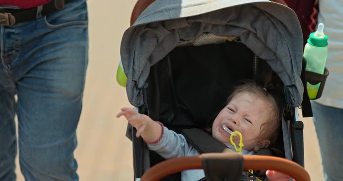 Kid is capricious in the stroller, sucking a pacifier in his mouth. Small child is being taken in a stroller, the baby is tired and crying. 4k, 10bit, ProRes
