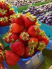 Baskets of bright red strawberries and purple blueberries at Granville Island Outdoor Public Market, Vancouver, Canada, shallow/depth of field, close up