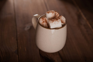 Marshmallows in a mug on a dark background close-up and copy space. Marshmallow in a cup with cocoa pattern top view in a dark key.