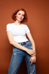 young pretty redhead girl posing cheerful on warm brown background, lifestyle people concept