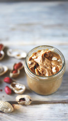 Selective focus. Peanut butter in a jar. Peanuts in the skin.
