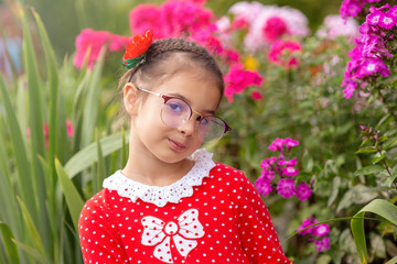 A portrait of beautiful little girl in glasses in garden