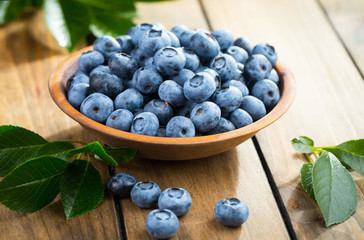 Blueberries in a plate and pancakes, on an old background.