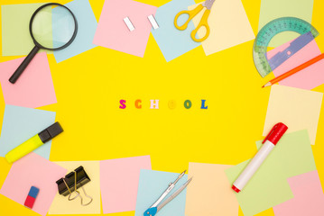 The word SCHOOL in the center on a yellow background, colored letters. Frame of empty note papers...