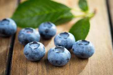 Ripe, fresh blueberries in a wooden bowl on an old background.
