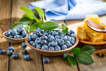 Ripe, fresh blueberries in a wooden bowl on an old background.