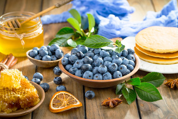 Blueberries in a plate and pancakes, on an old background.