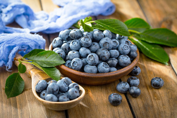 Ripe, fresh blueberries in a wooden bowl on an old background.