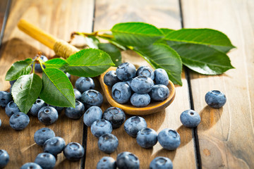 Ripe, fresh blueberries in a wooden bowl on an old background.