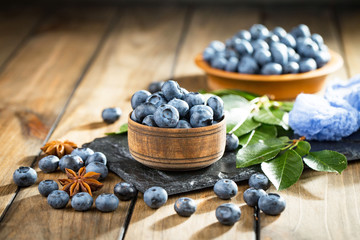 Ripe, fresh blueberries in a wooden bowl on an old background.