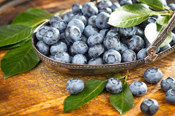 Blueberries in a plate and pancakes, on an old background.