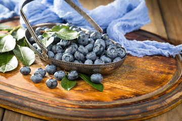 Blueberries in a plate and pancakes, on an old background.