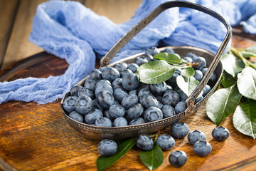 Ripe, fresh blueberries in a wooden bowl on an old background.