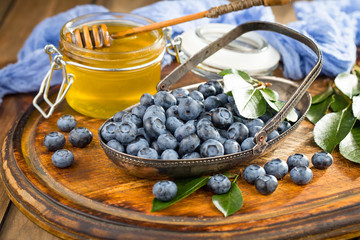 Ripe, fresh blueberries in a wooden bowl on an old background.