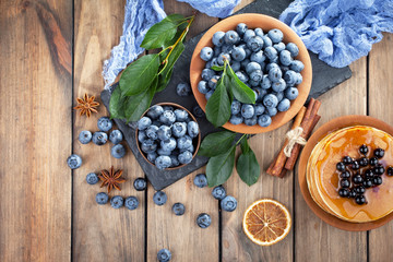 Blueberries in a plate and pancakes, on an old background.