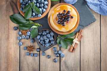 Blueberries in a plate and pancakes, on an old background.